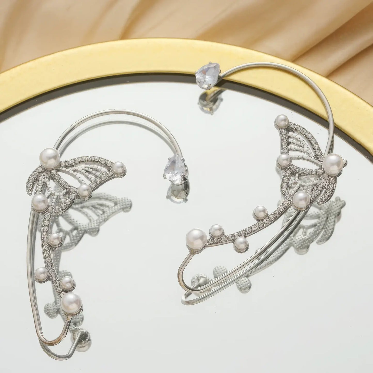 Silver diamond butterfly ear cuff, placed on mirror, elaborate butterfly & pearl design