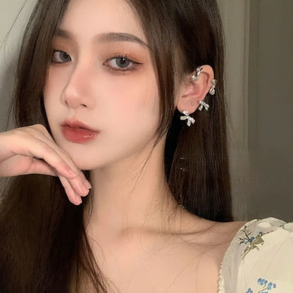 Another full - face view of silver diamond - encrusted bow ear cuff worn on model