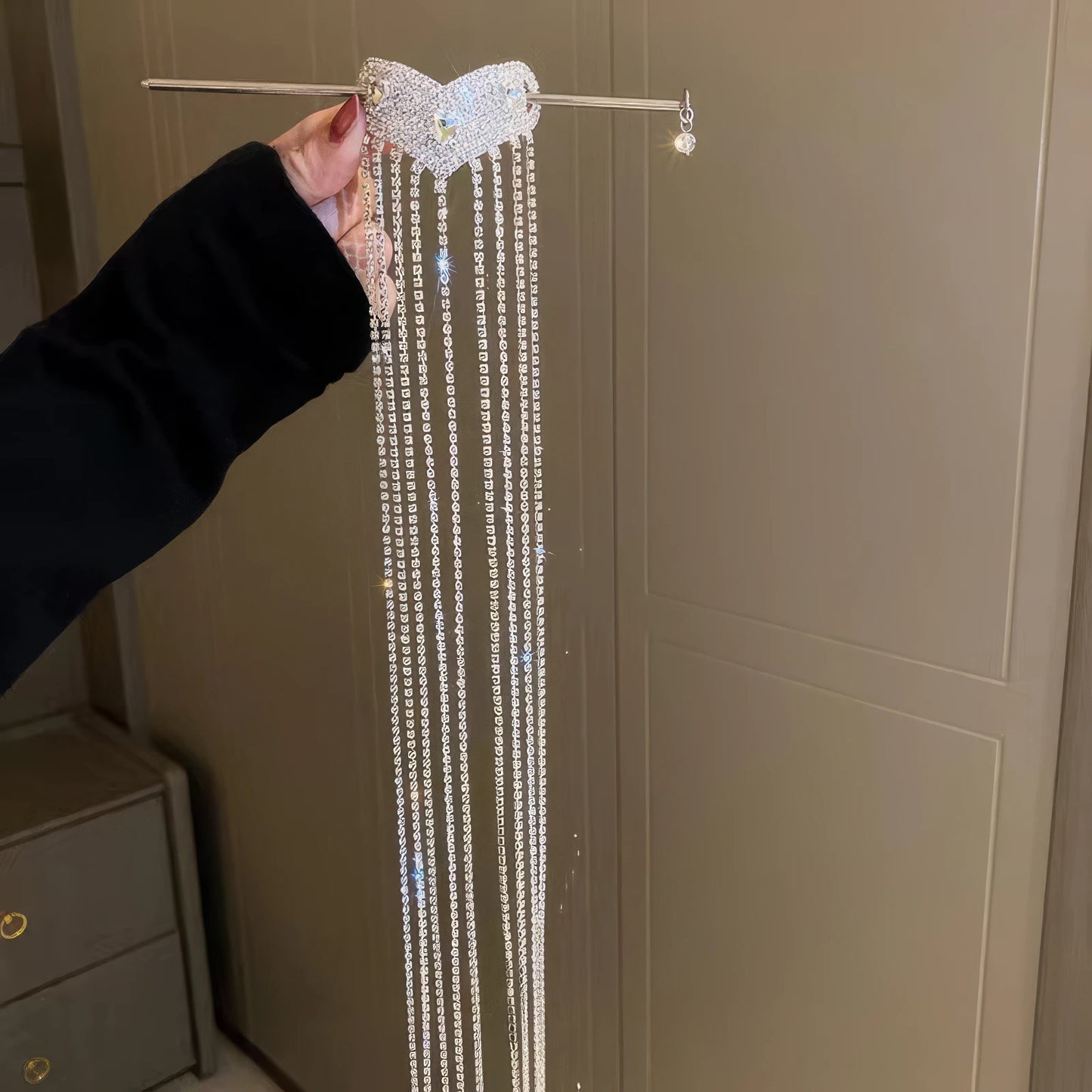 Hand holding silver diamond heart extra - long tassel hairpin, light background