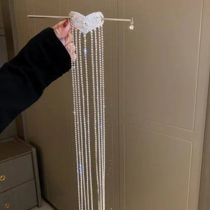 Hand holding silver diamond heart extra - long tassel hairpin, light background