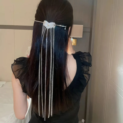Silver diamond heart extra - long tassel hairpin worn in a half - up hairstyle, black clothing background