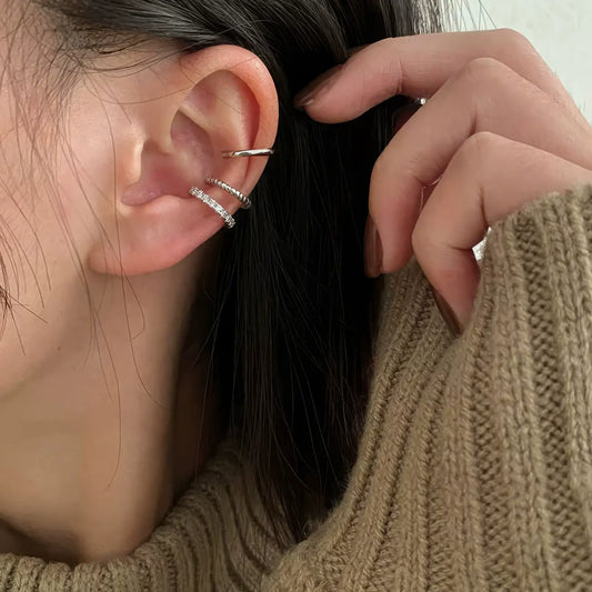 Silver diamond - row ear cuffs worn, complementing a brown sweater, showcasing an elegant look
