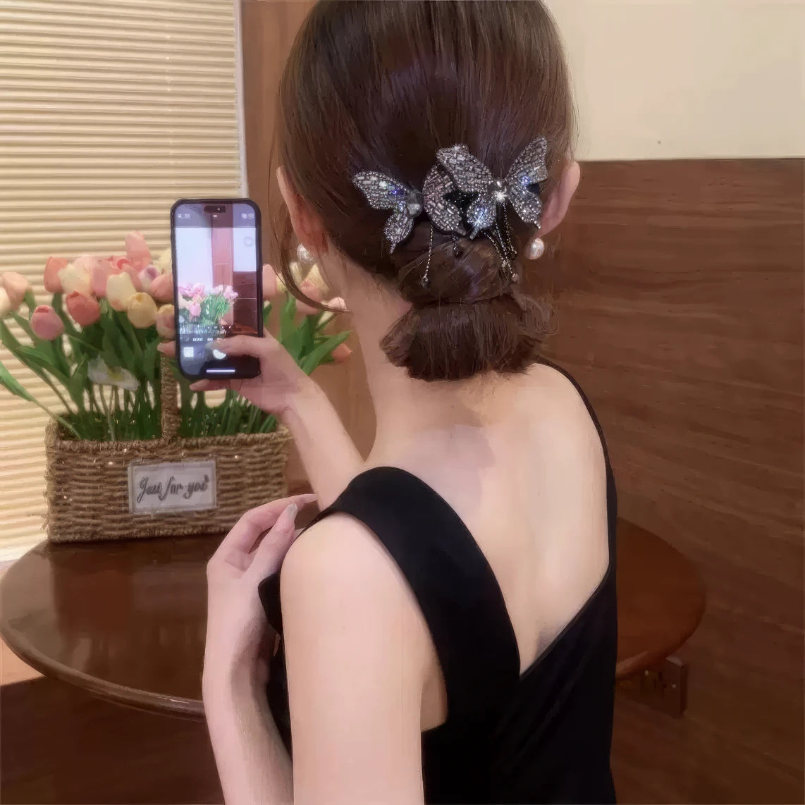 Silver double butterfly tassel hair clip worn in a half - up hairstyle, black clothing background, taking mirror selfie