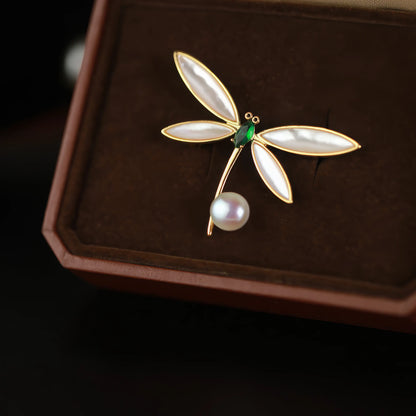 Dragonfly brooch with pearl, placed in brown box, showcasing elegant design