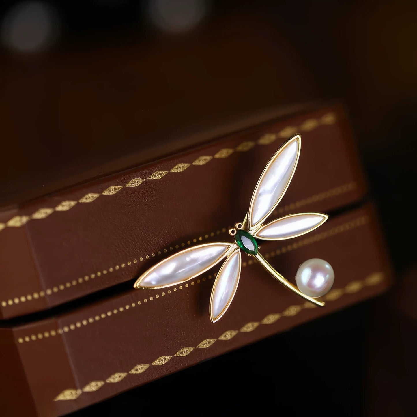 Dragonfly brooch with pearl, placed in luxury brown box, showcasing craftsmanship