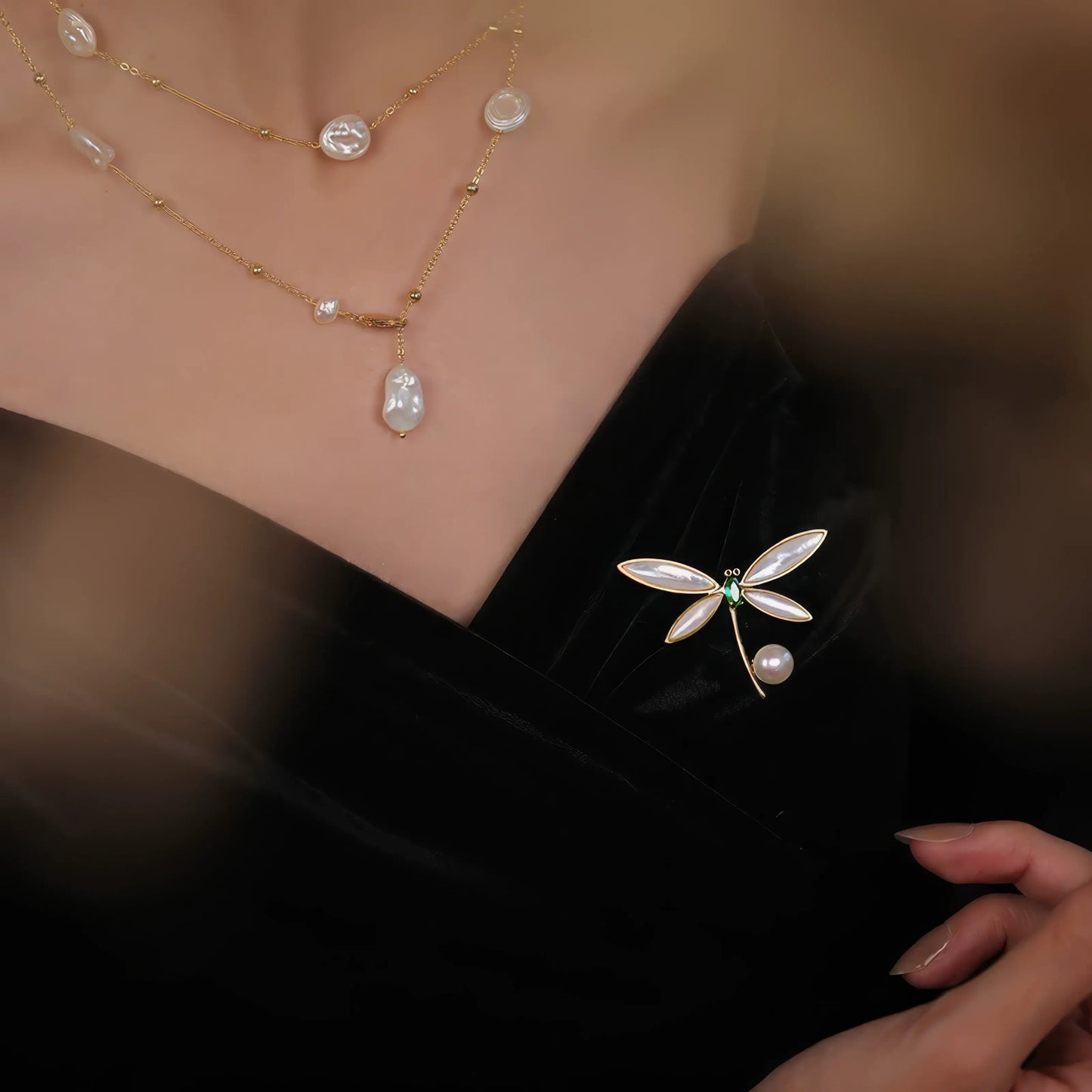 Dragonfly brooch with pearl, worn on black dress, highlighting delicate style