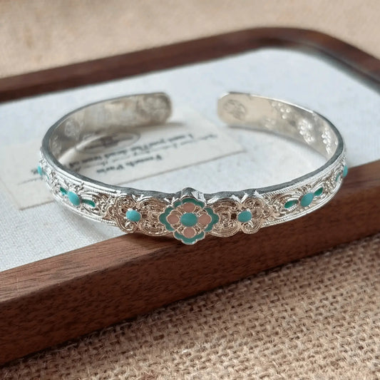 Enamel open bangle displayed on a wooden tray with card, beige background