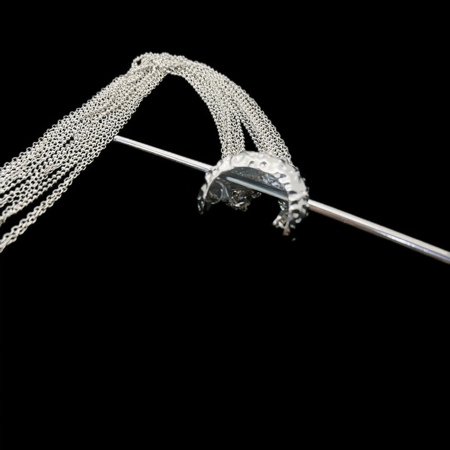 Close - up detail of extra - long tassel hairpin, black background