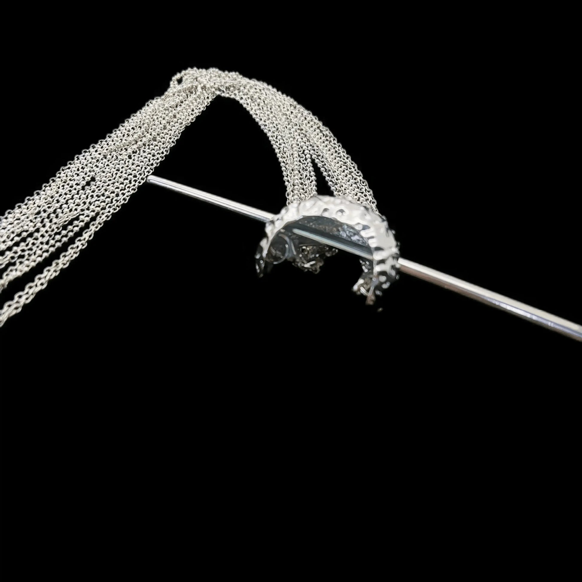 Close - up detail of extra - long tassel hairpin, black background