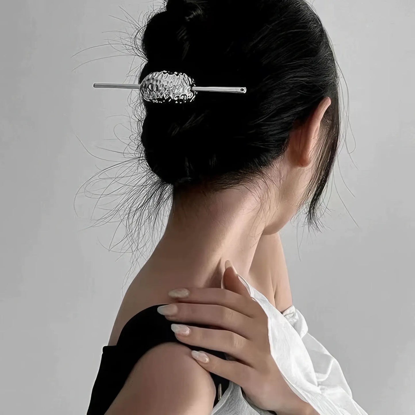 Extra - long tassel hairpin worn in an updo hairstyle, light background