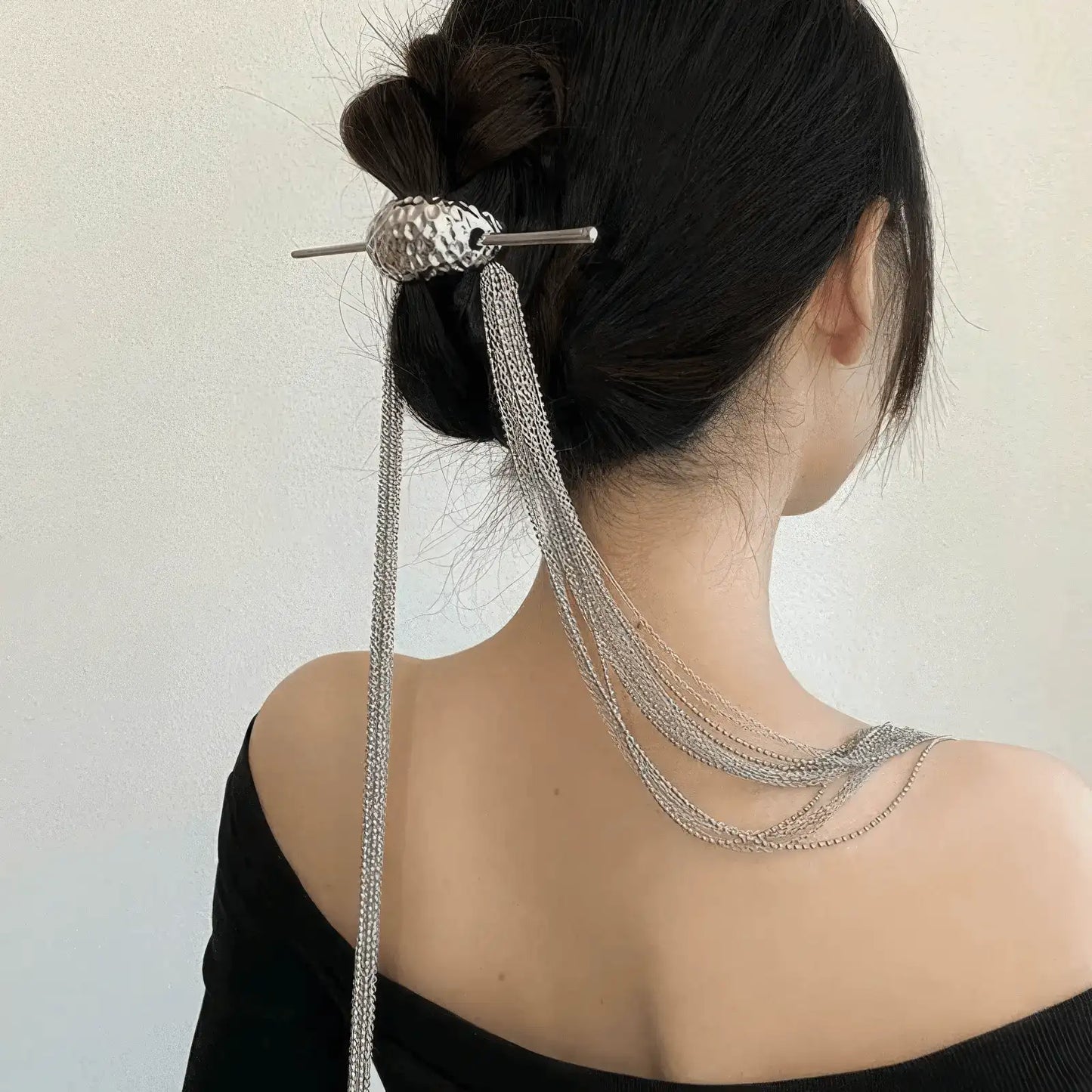 Extra - long tassel hairpin worn in an updo hairstyle, showcasing tassel flow, light background