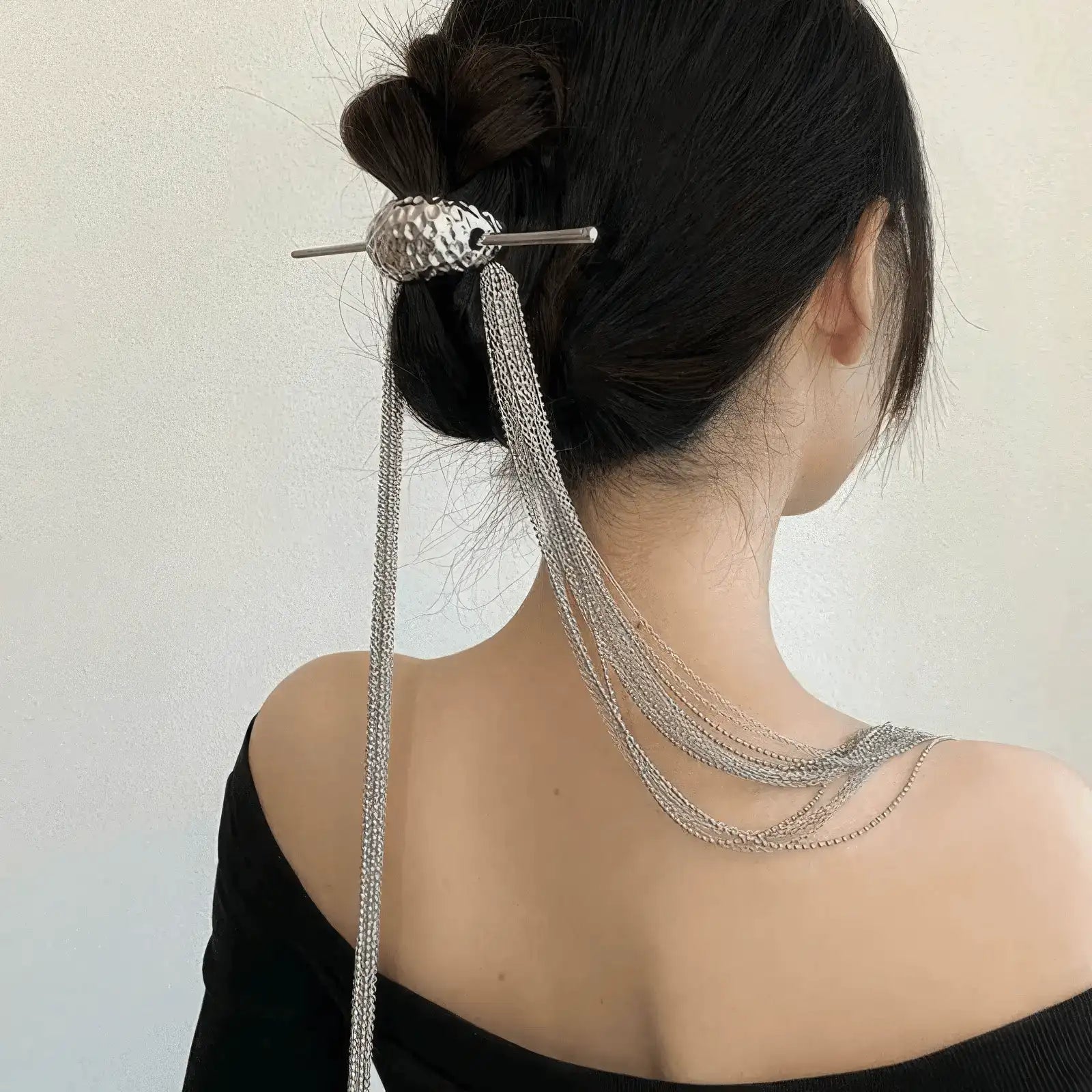 Extra - long tassel hairpin worn in an updo hairstyle, showcasing tassel flow, light background