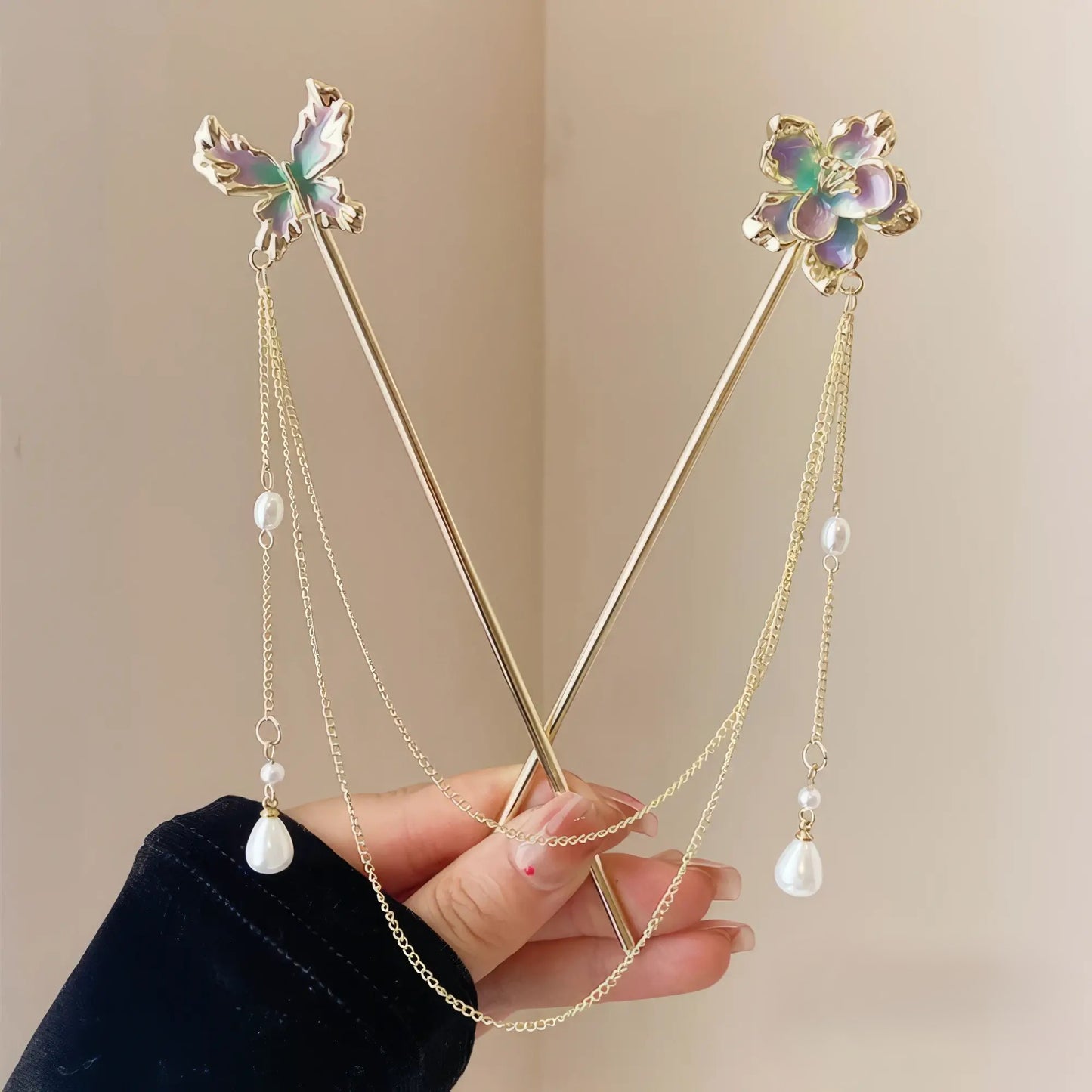 Floral butterfly hairpins crossed in hand, showcasing pearl chains