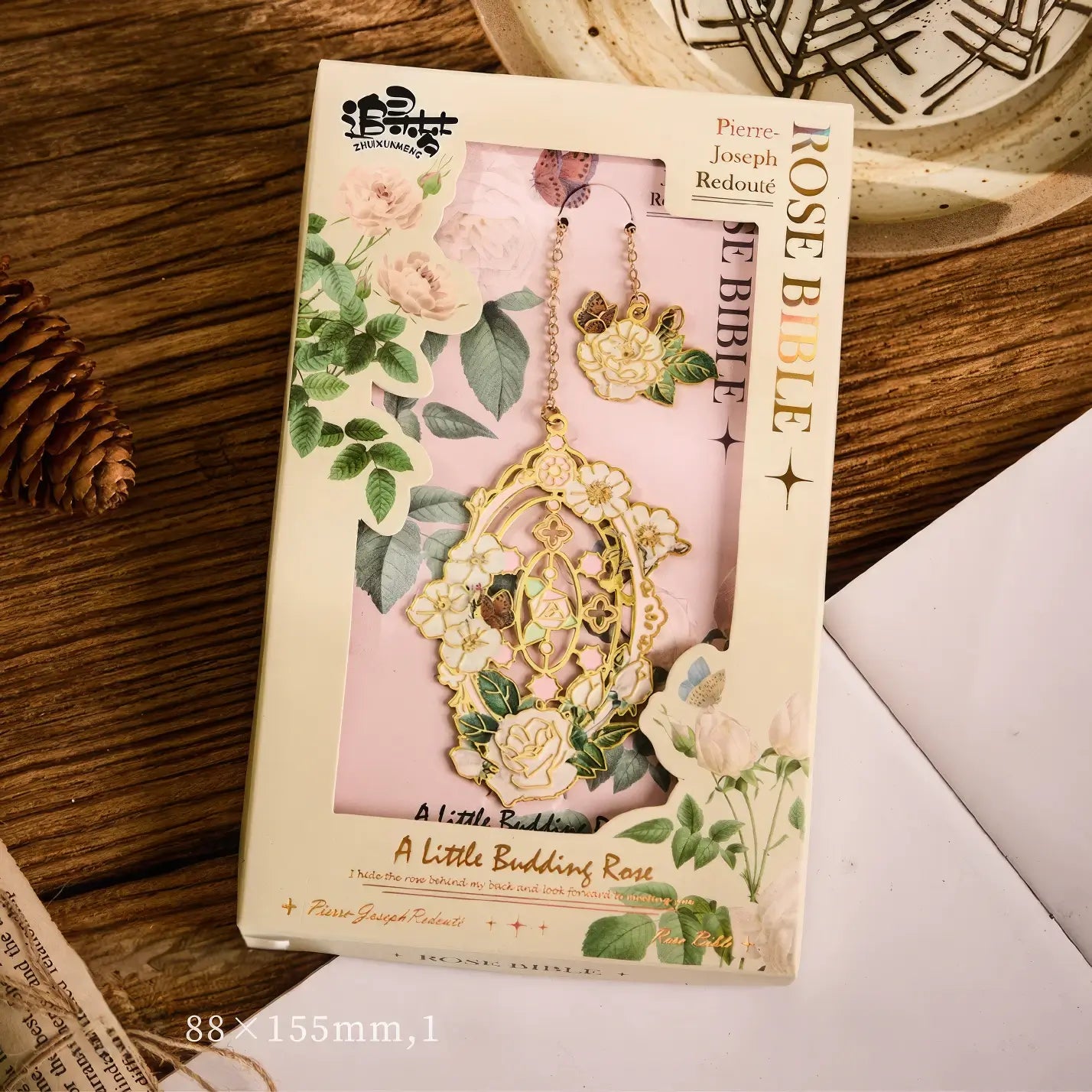 Floral story bookmark in beige package, displayed on wooden surface with stationery in background