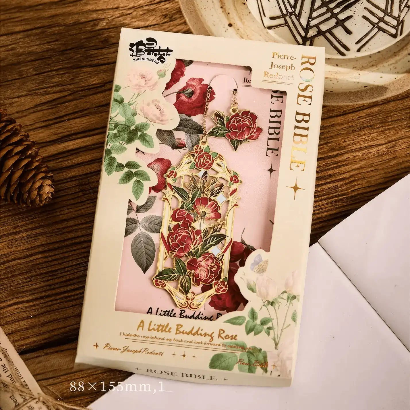 Floral story bookmark in beige package, displayed on wooden surface with stationery in background