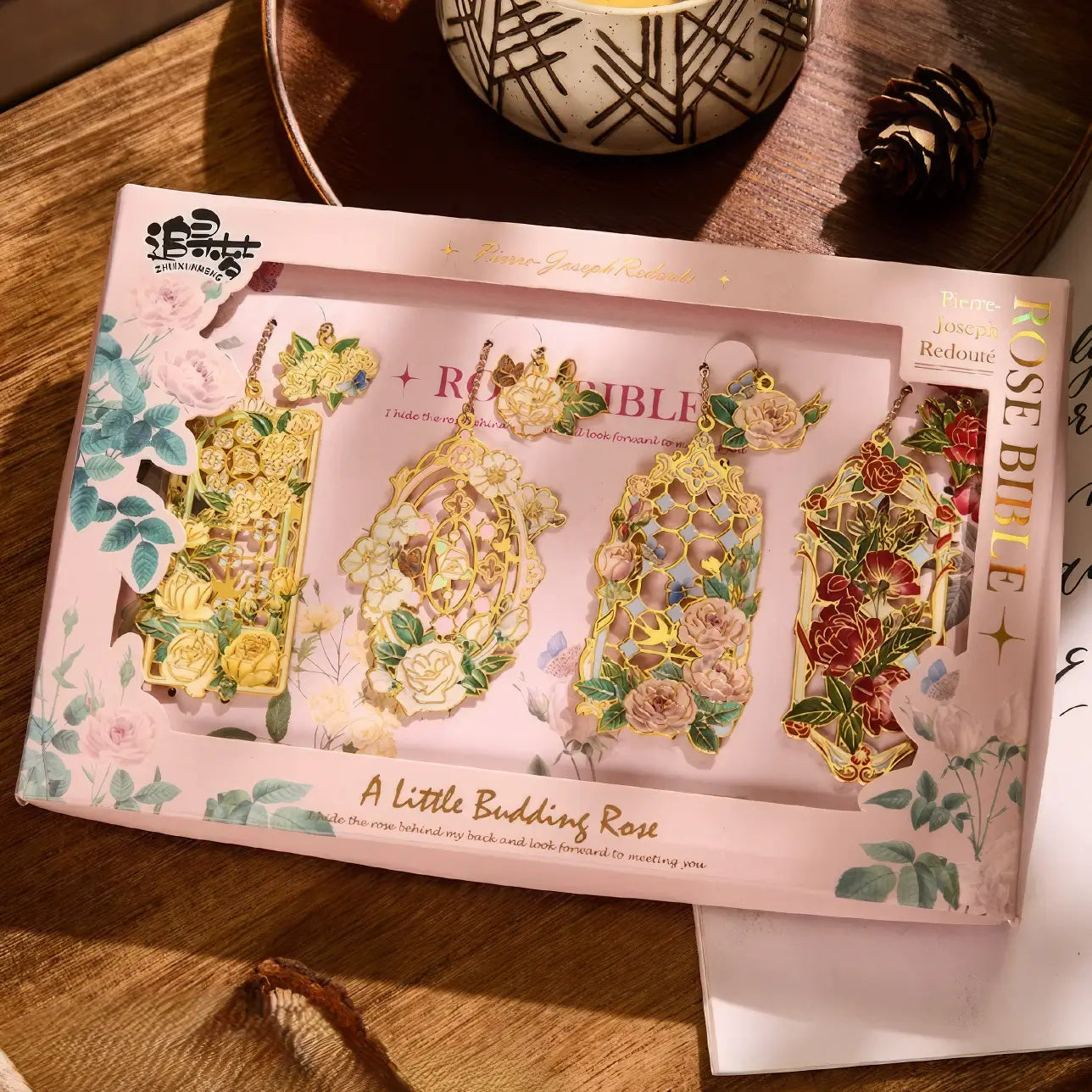 Floral story bookmark in pink package, displayed on wooden surface with stationery in background