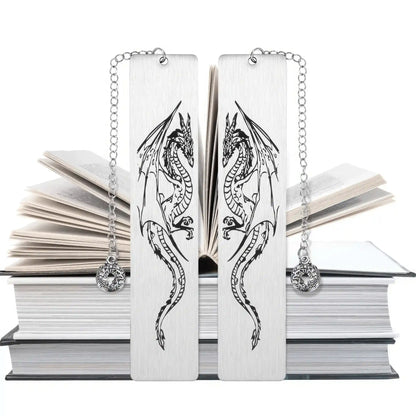Pair of white four - winged dragon metal bookmarks, displayed on stacked books