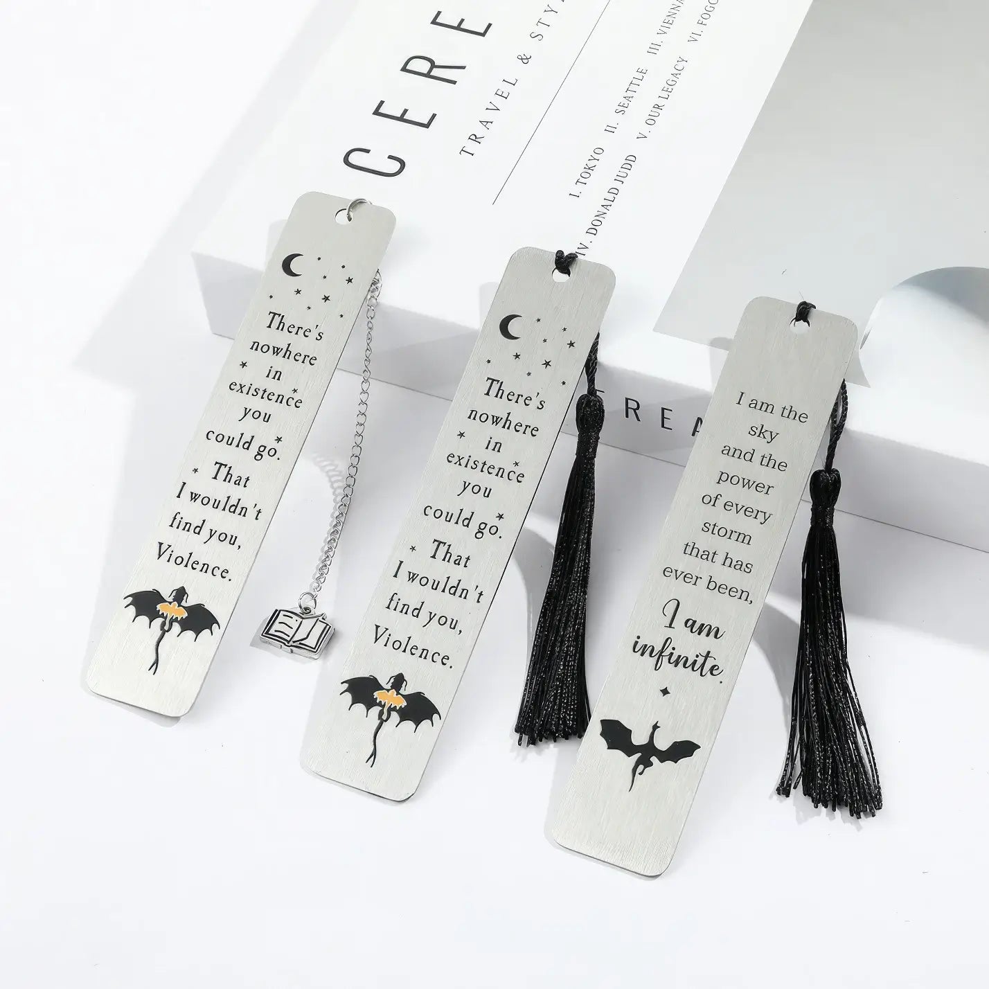 Set of white four - winged dragon metal bookmarks with tassels, displayed on white background