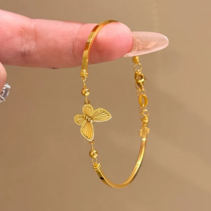 Hand holding gold butterfly bracelet, close - up view