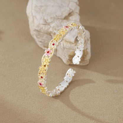 Gold - outlined flower bangle leaning on rock, emphasizing 3D structure