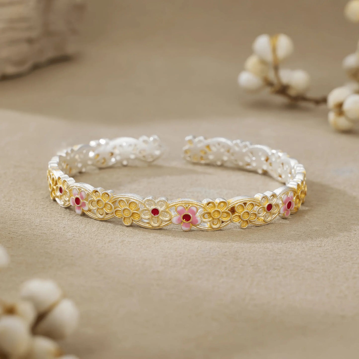 Gold - outlined flower bangle placed with white buds, showcasing delicate design