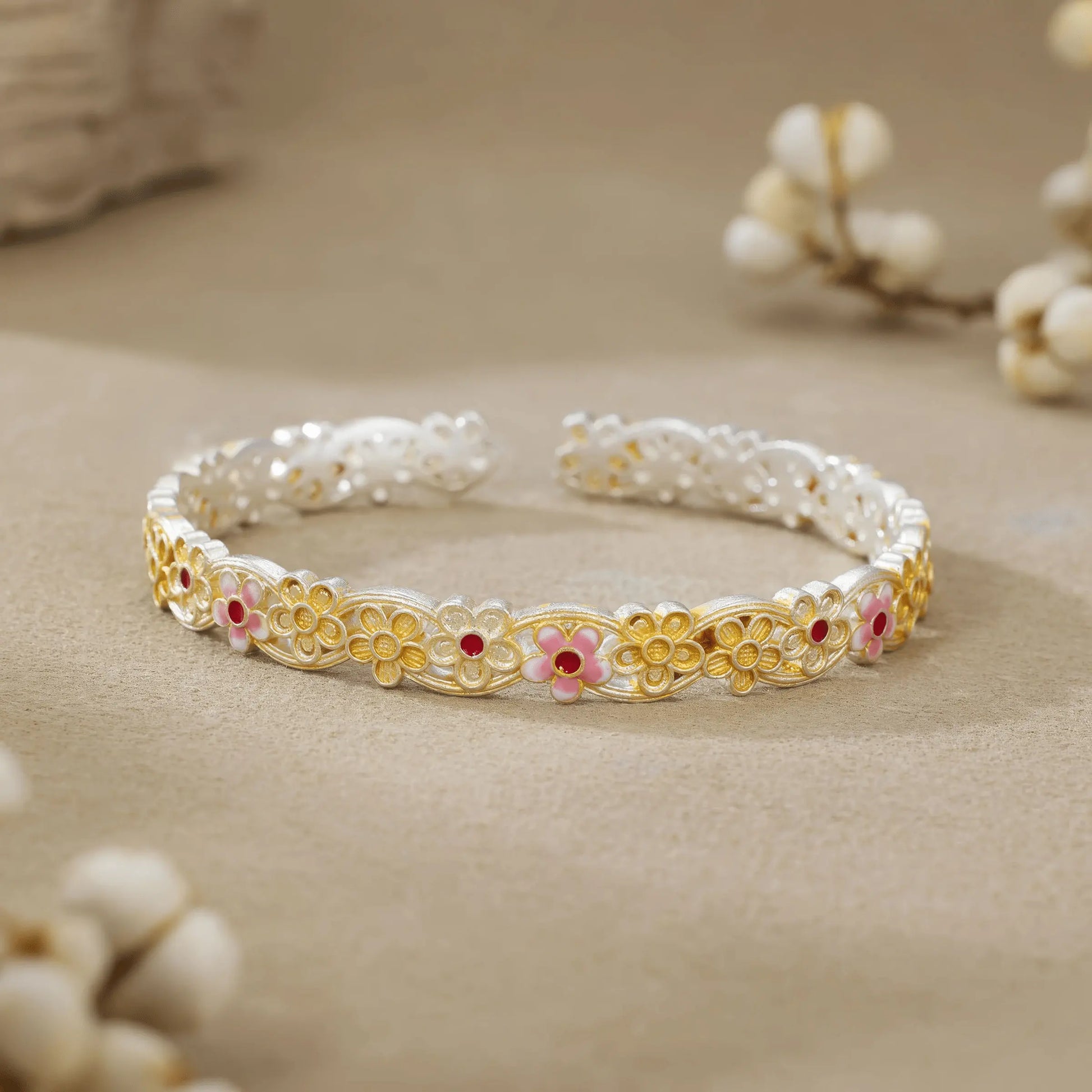 Gold - outlined flower bangle placed with white buds, showcasing delicate design