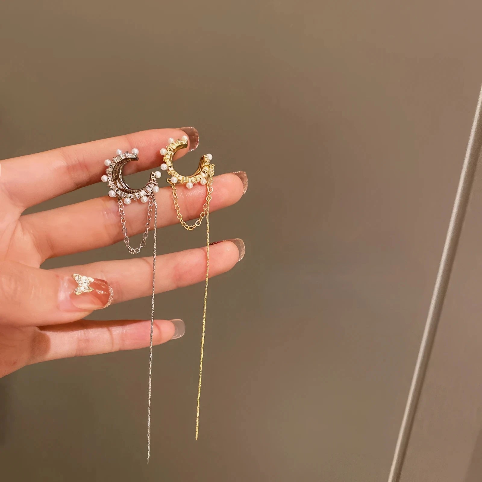 Hands holding gold and silver tassel diamond earrings
