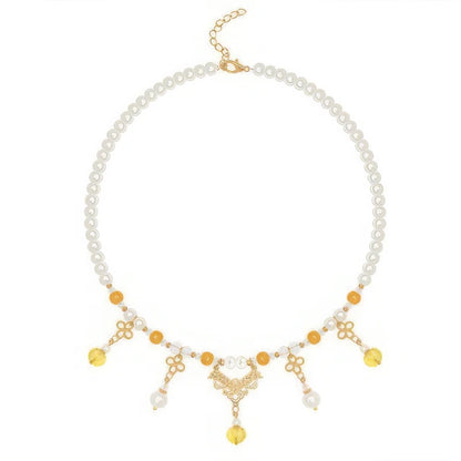 Gold - sprinkled pumpkin necklace with pearls and yellow beads, isolated on white background