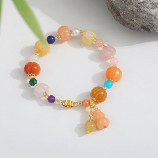 Golden silk jade agate pumpkin bead bracelet with multicolor accents on a light surface