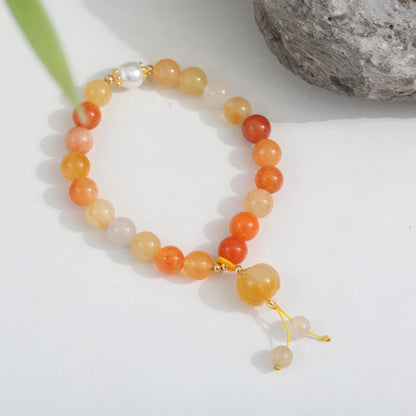 Golden silk jade agate pumpkin bead bracelet with simple pendant on a light surface