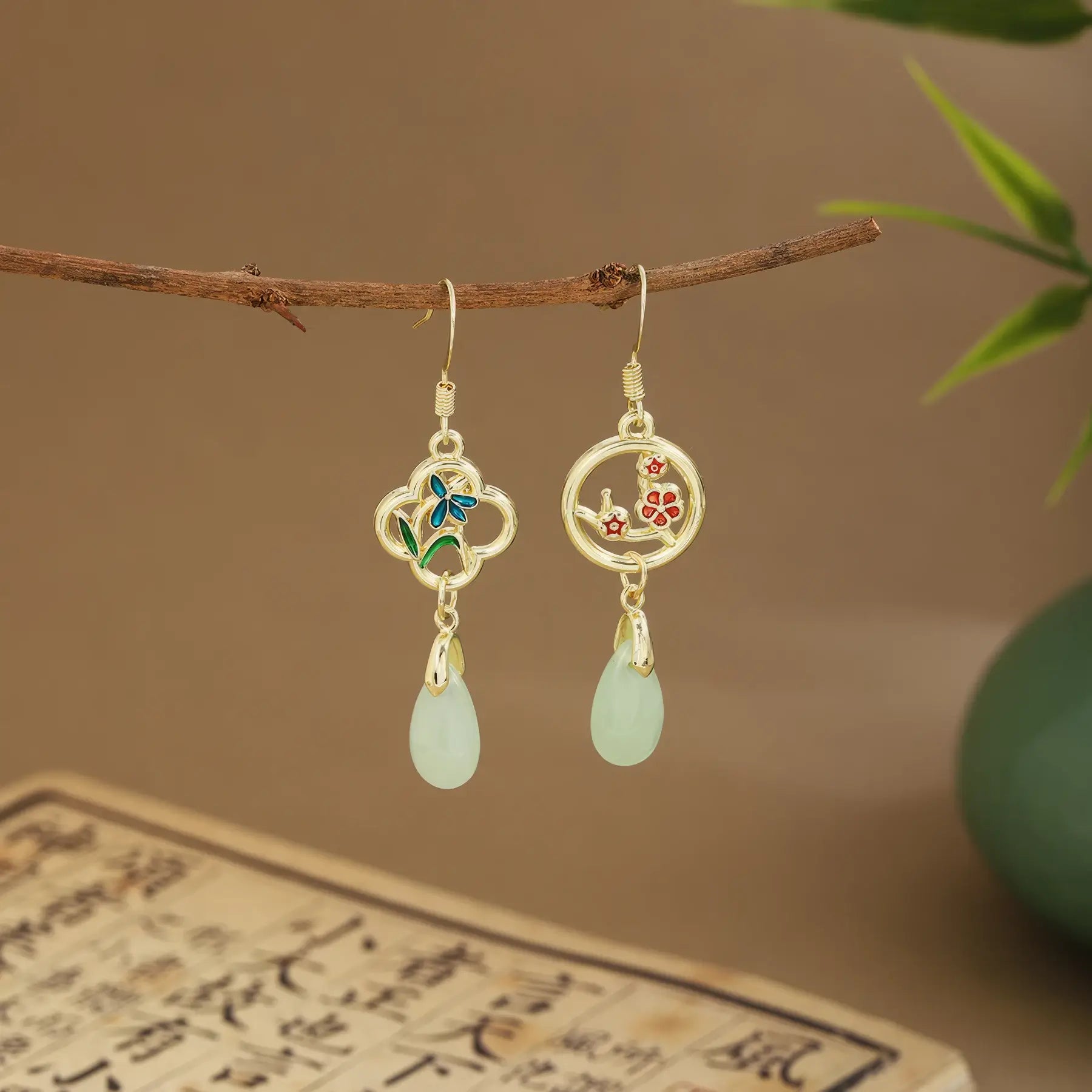 Mixed fan earrings with light green drops on wooden hanger, green vase and scroll