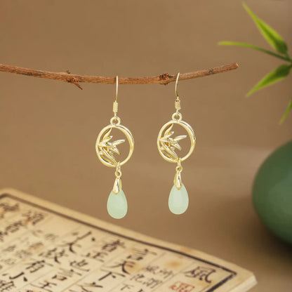 Bamboo - themed earrings with light green drops on wooden hanger, green vase and scroll