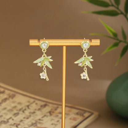 Floral fan earrings with dark green drops on wooden hanger, green vase and scroll