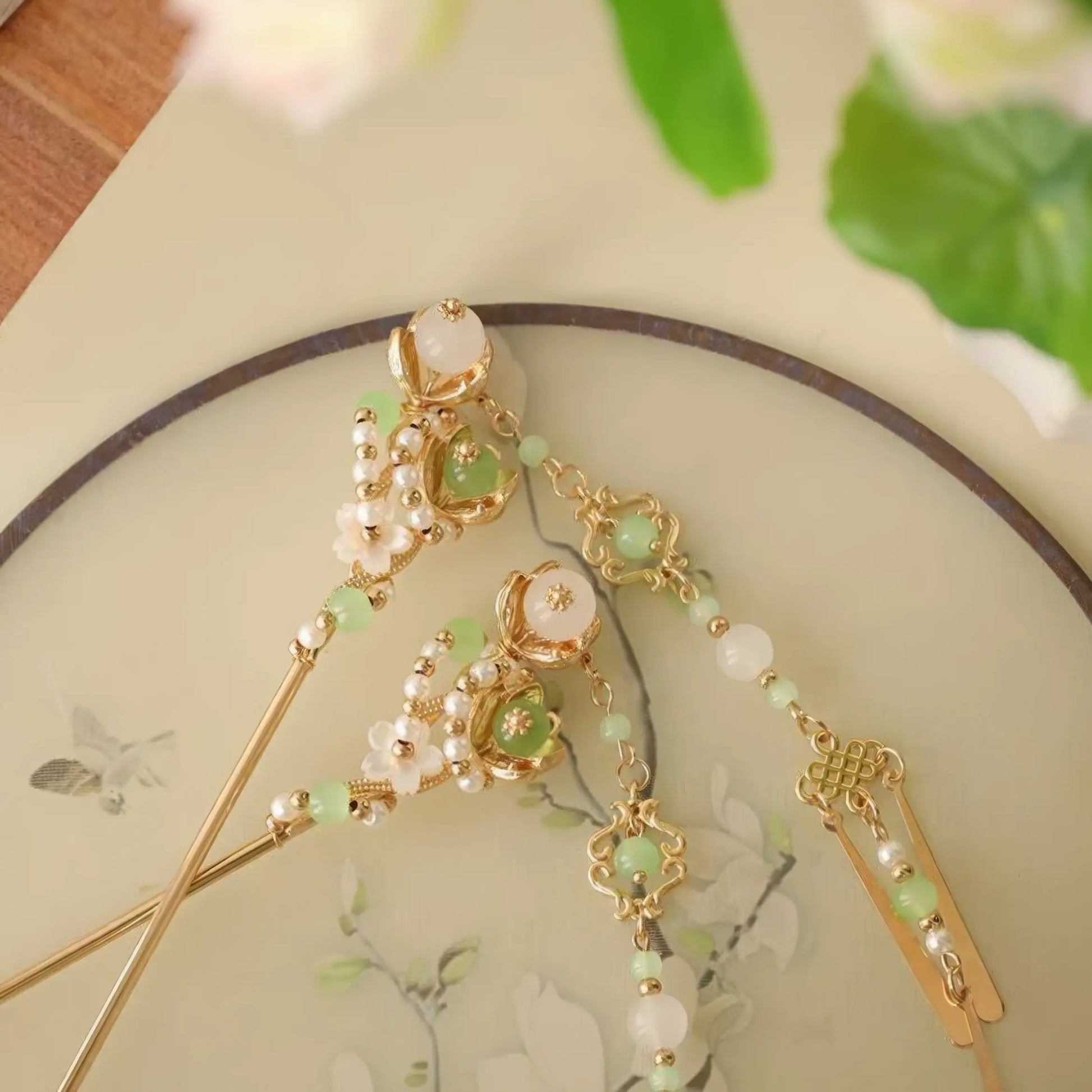 Close-up of green jade, pearl, and gold hairpins with intricate floral and knot designs.