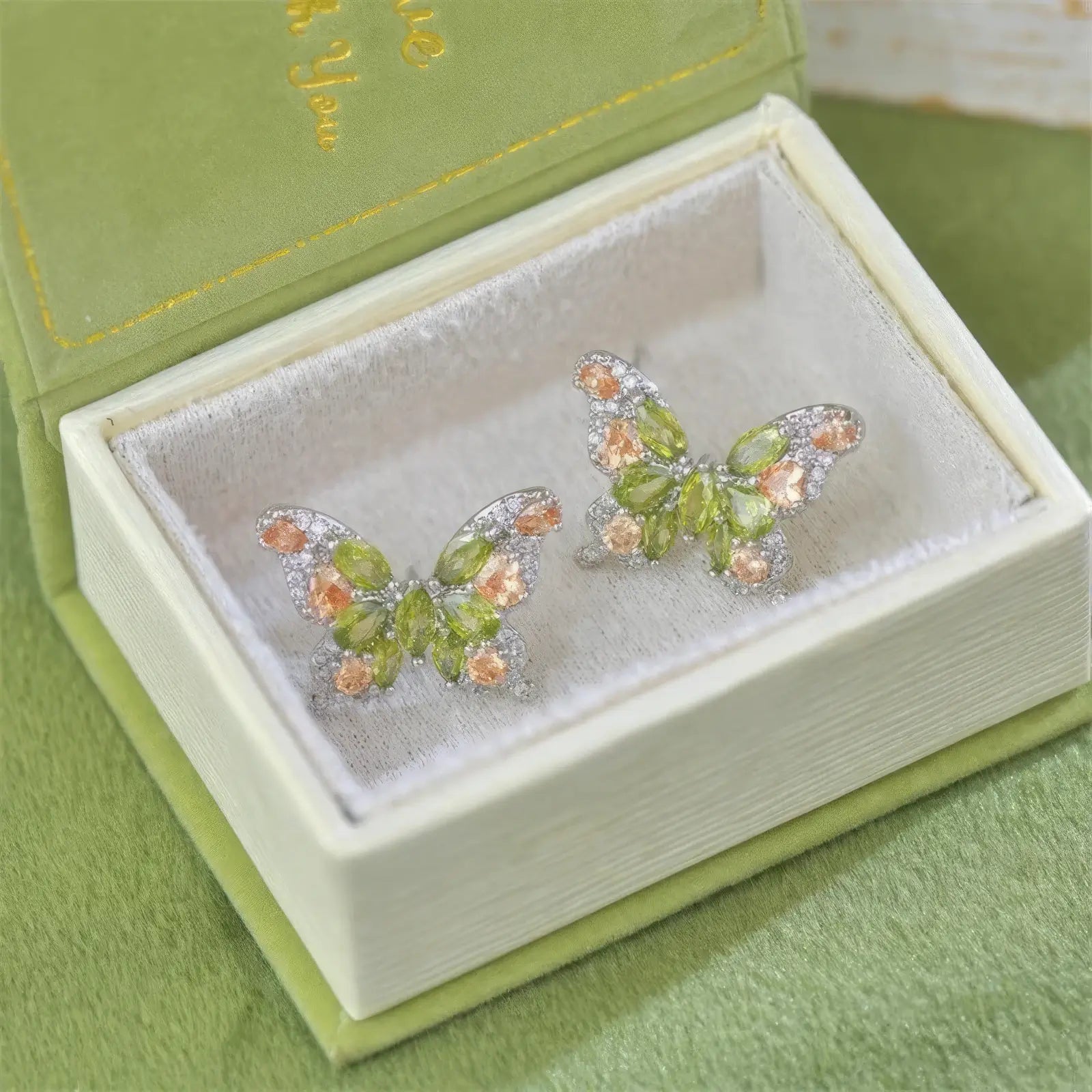 Green zircon butterfly earrings in an open green box