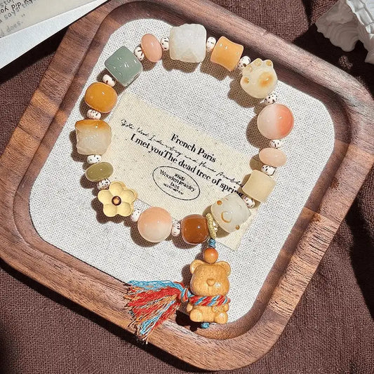 Another heart bear lion bodhi bracelet displayed on a wooden tray with card
