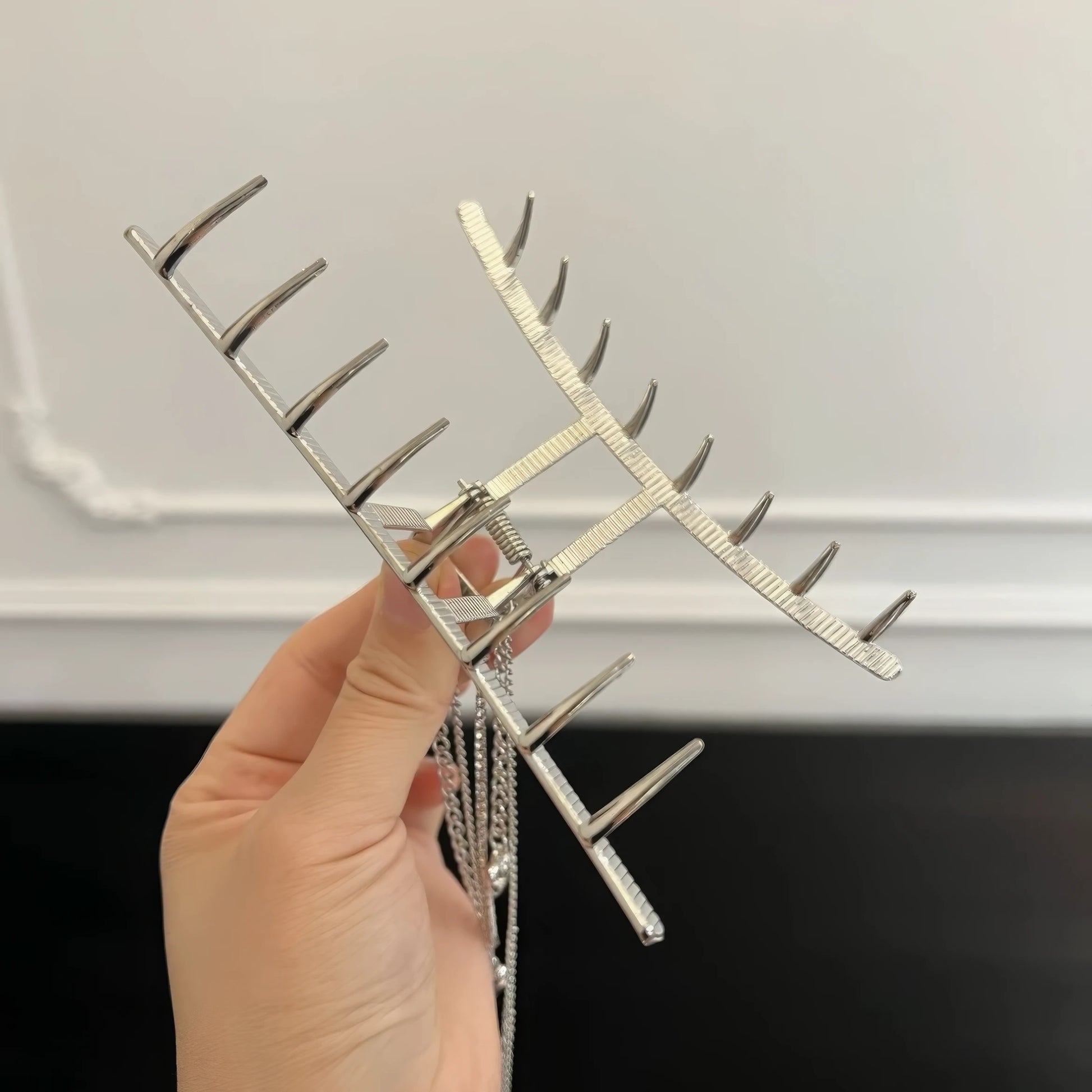 Hand holding silver heart - shaped tassel chain hair claw, showcasing design