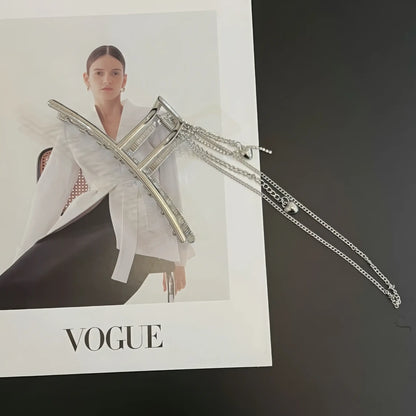 Silver heart - shaped tassel chain hair claw placed with "VOGUE" magazine, highlighting style