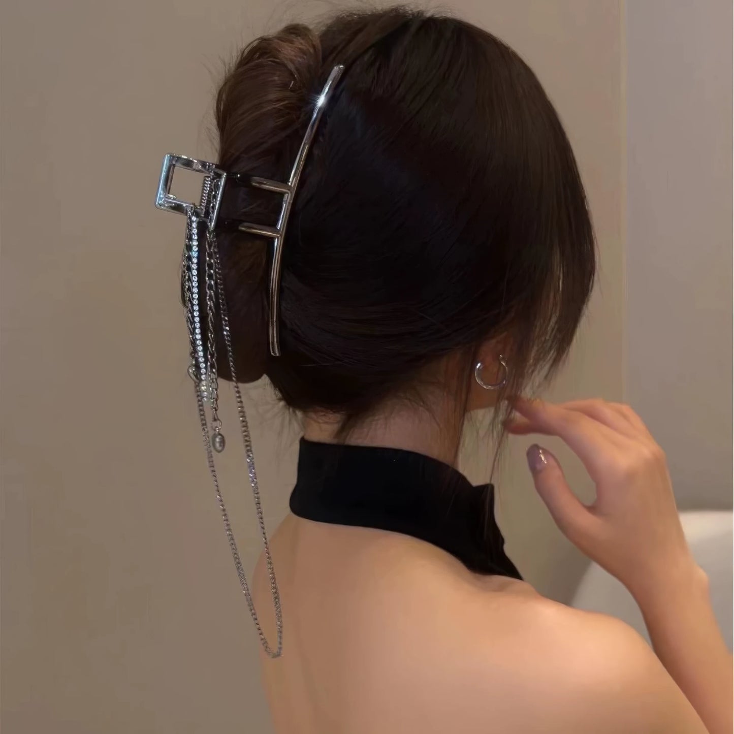 Silver heart - shaped tassel chain hair claw worn in updo hairstyle, model in black top