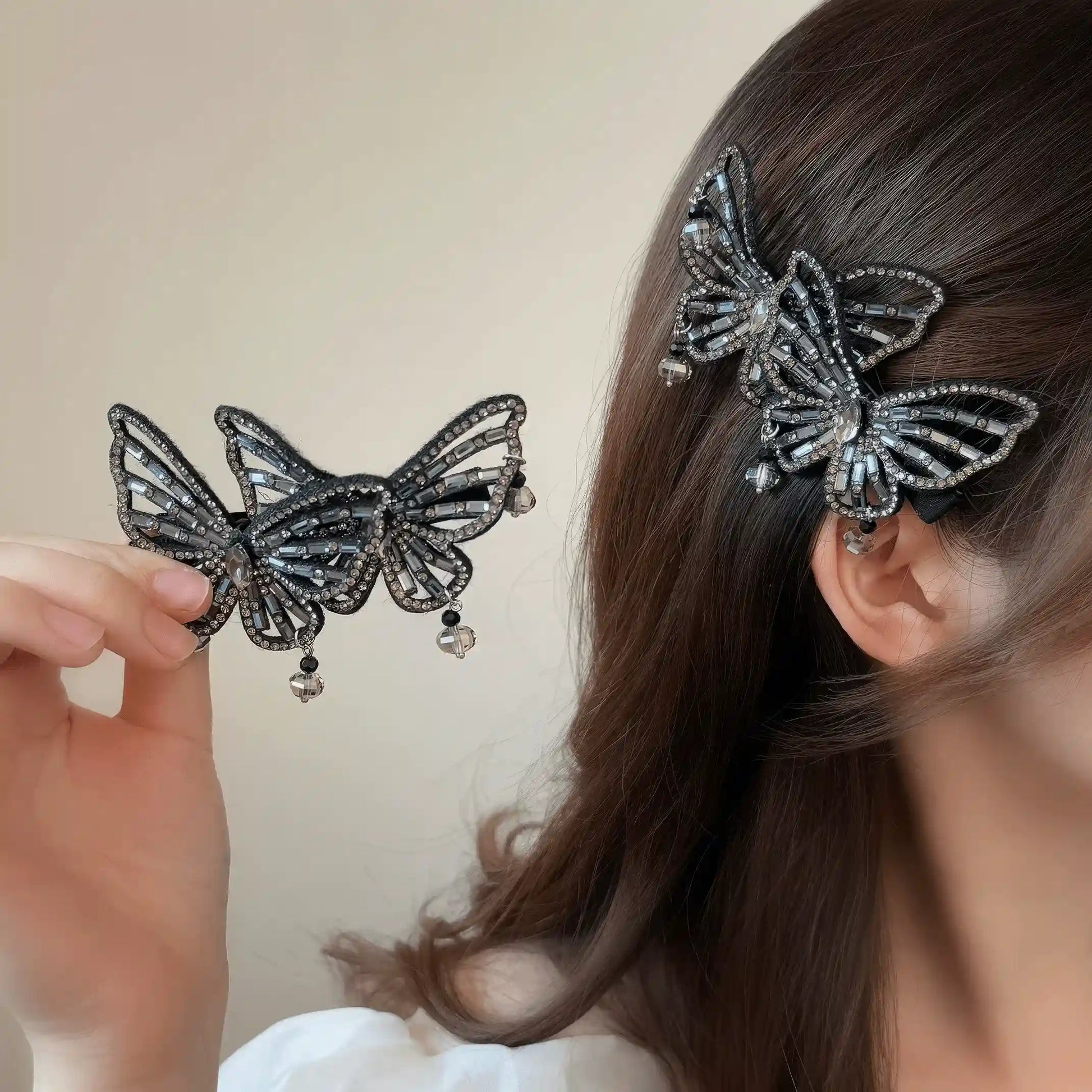 Hand holding hollow butterfly hair clip, worn in side hairstyle, light background