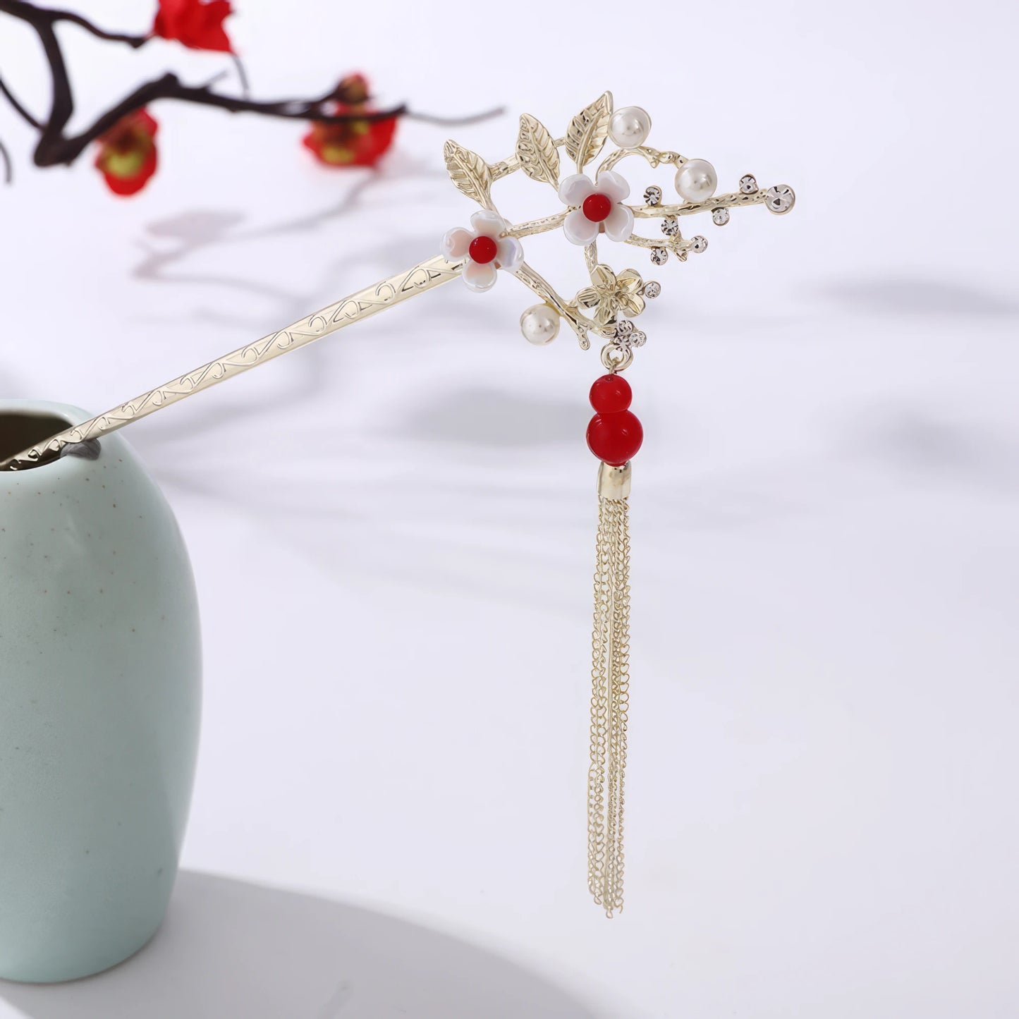 Houtinghua hairpin featuring red beads, floral design and gold tassel, in light green vase