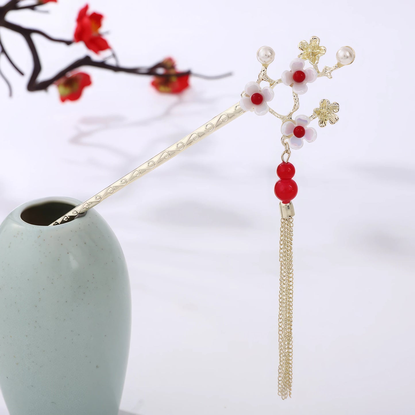 Houtinghua hairpin featuring red beads, floral design and gold tassel, in light green vase