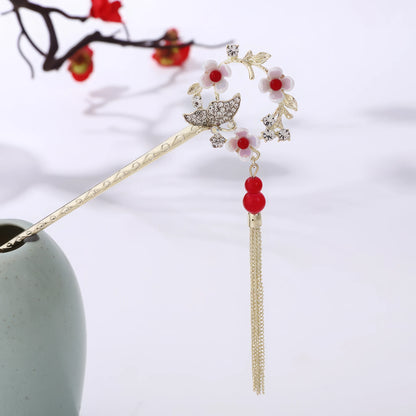 Houtinghua hairpin featuring red beads, floral design and gold tassel, in light green vase