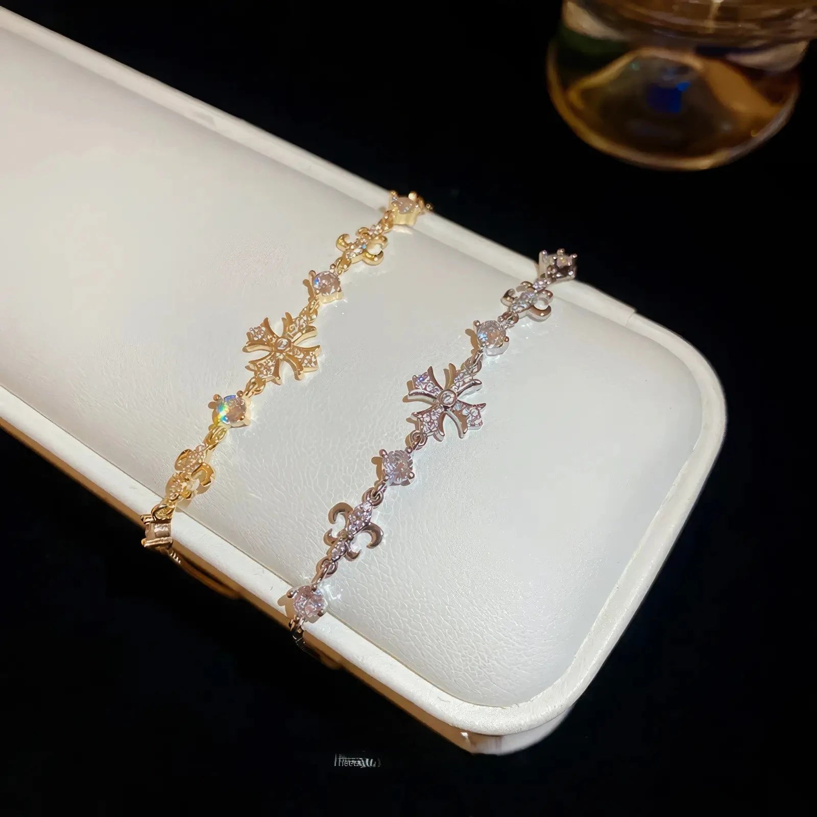 Iris cross bracelets, gold and silver - tone, displayed on white pad