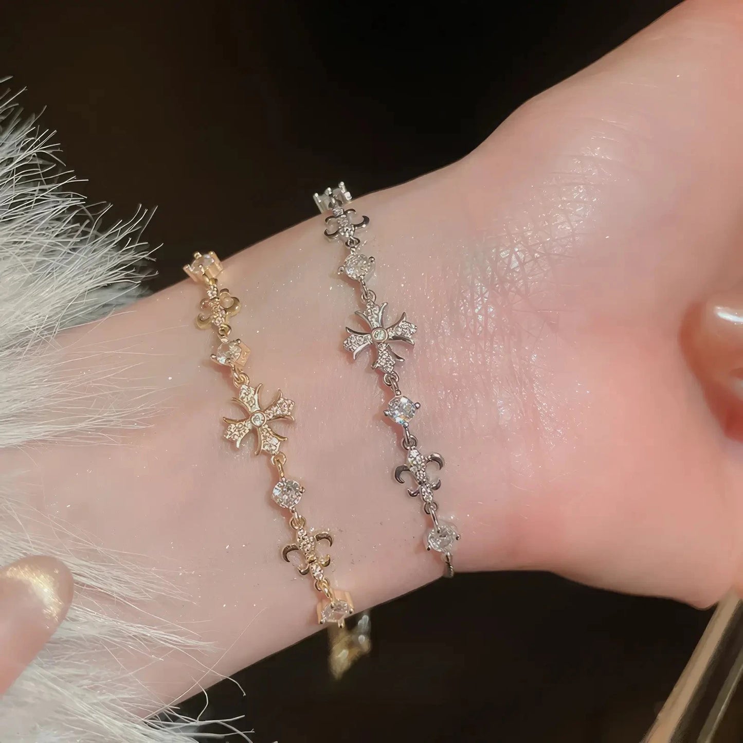 Iris cross bracelets, gold and silver - tone, worn on wrist with fur trim