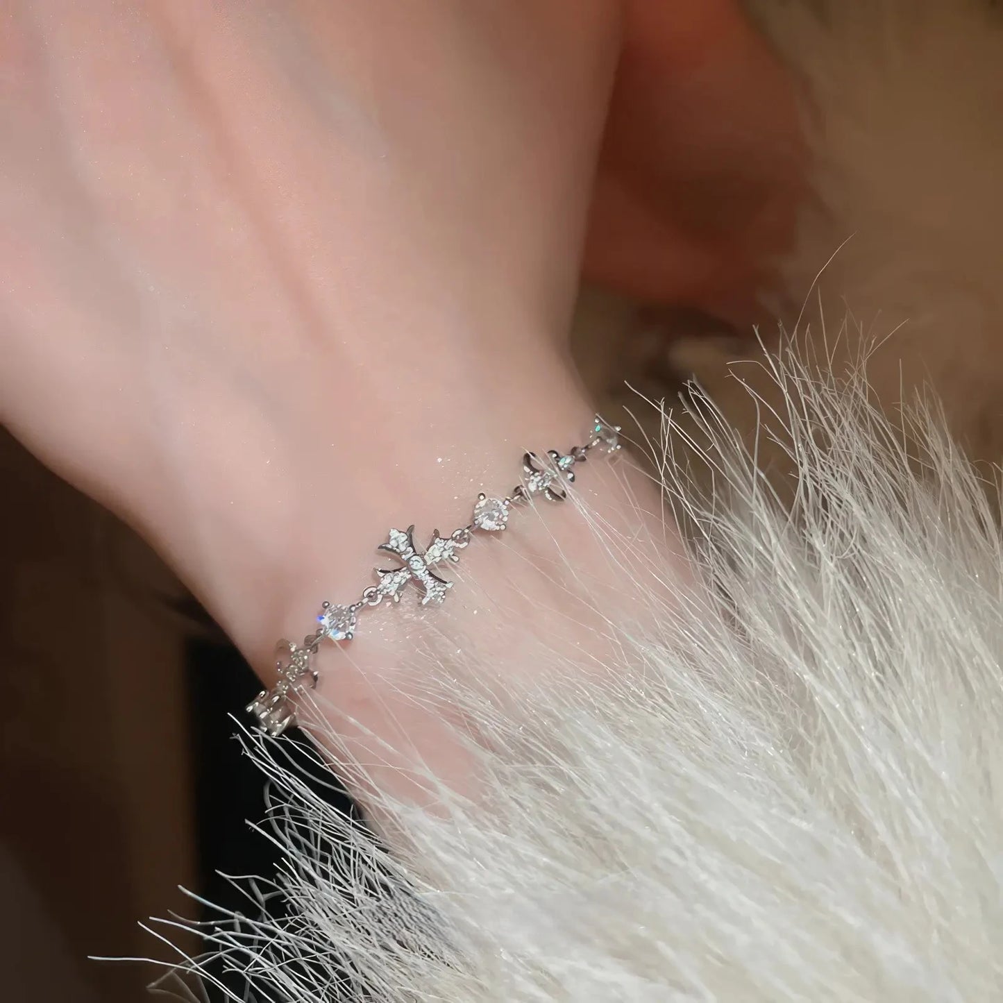 Iris cross bracelet, silver - tone, worn on wrist with fur trim