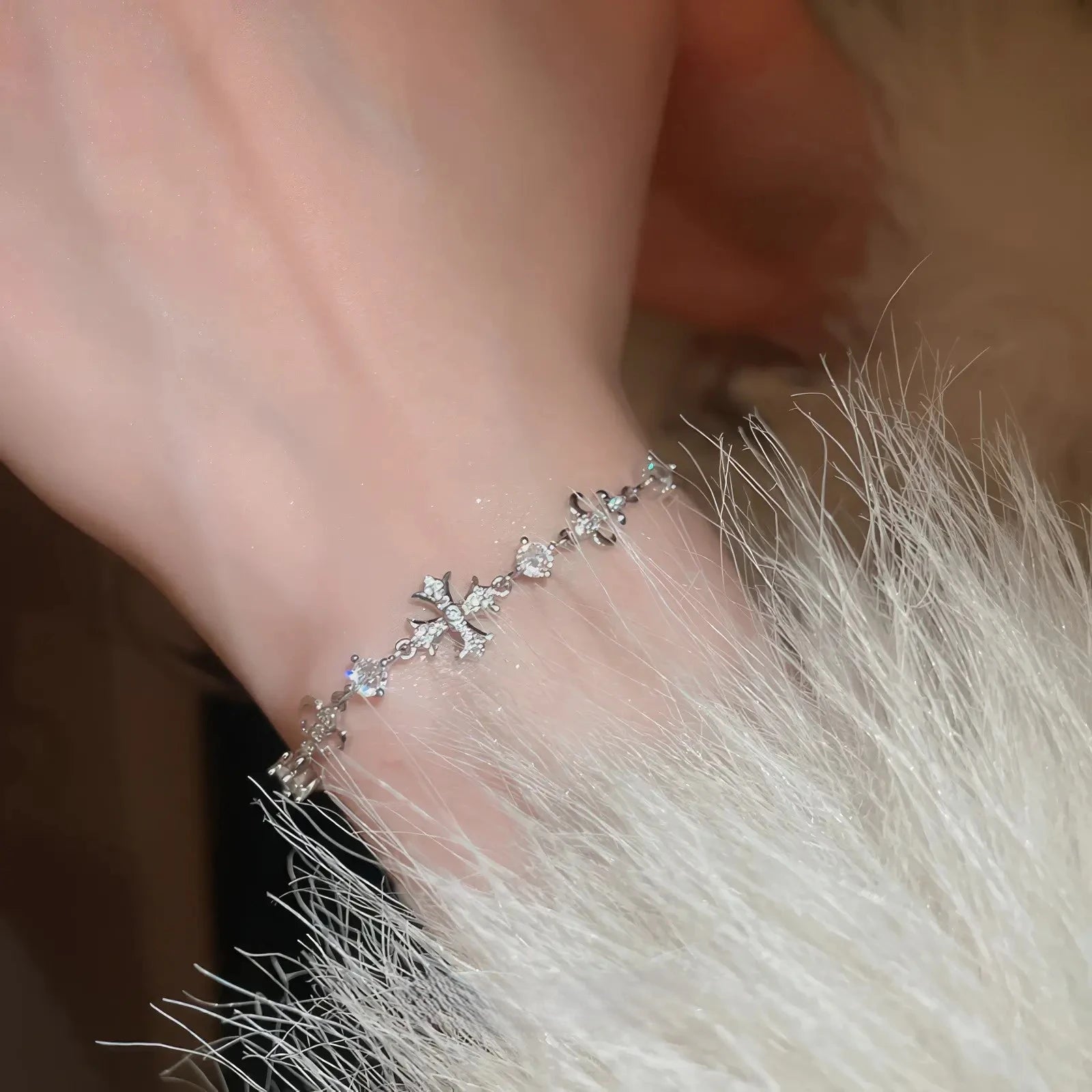 Iris cross bracelet, silver - tone, worn on wrist with fur trim