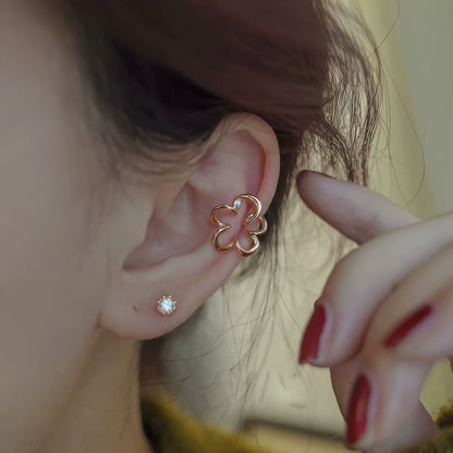 Gold irregular flower ear clips worn, with hand adjusting, emphasizing the delicate and unique shape