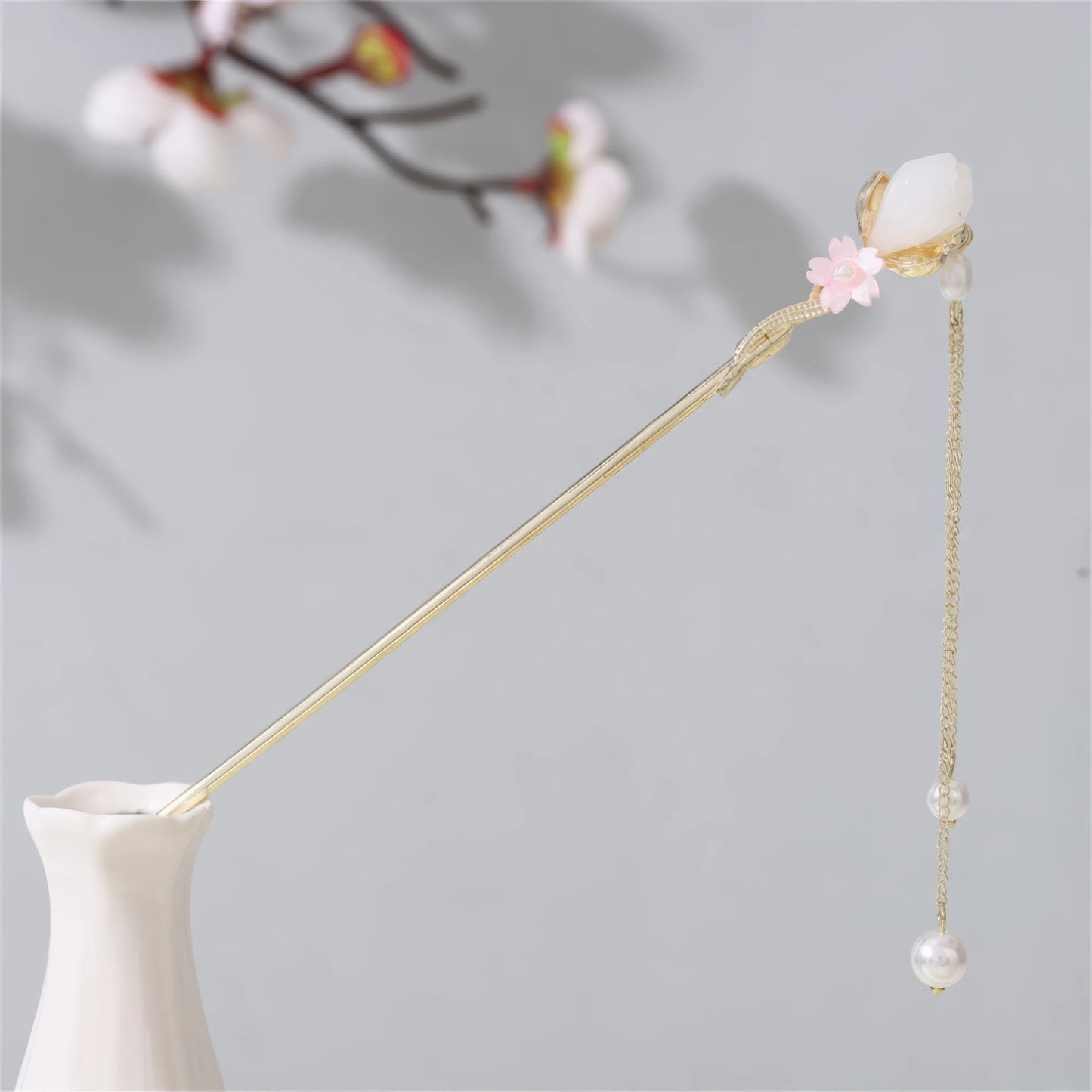 Jianjianjiao hairpin 1, gold rod with pearl and flower, in white vase against light gray background with plum blossoms