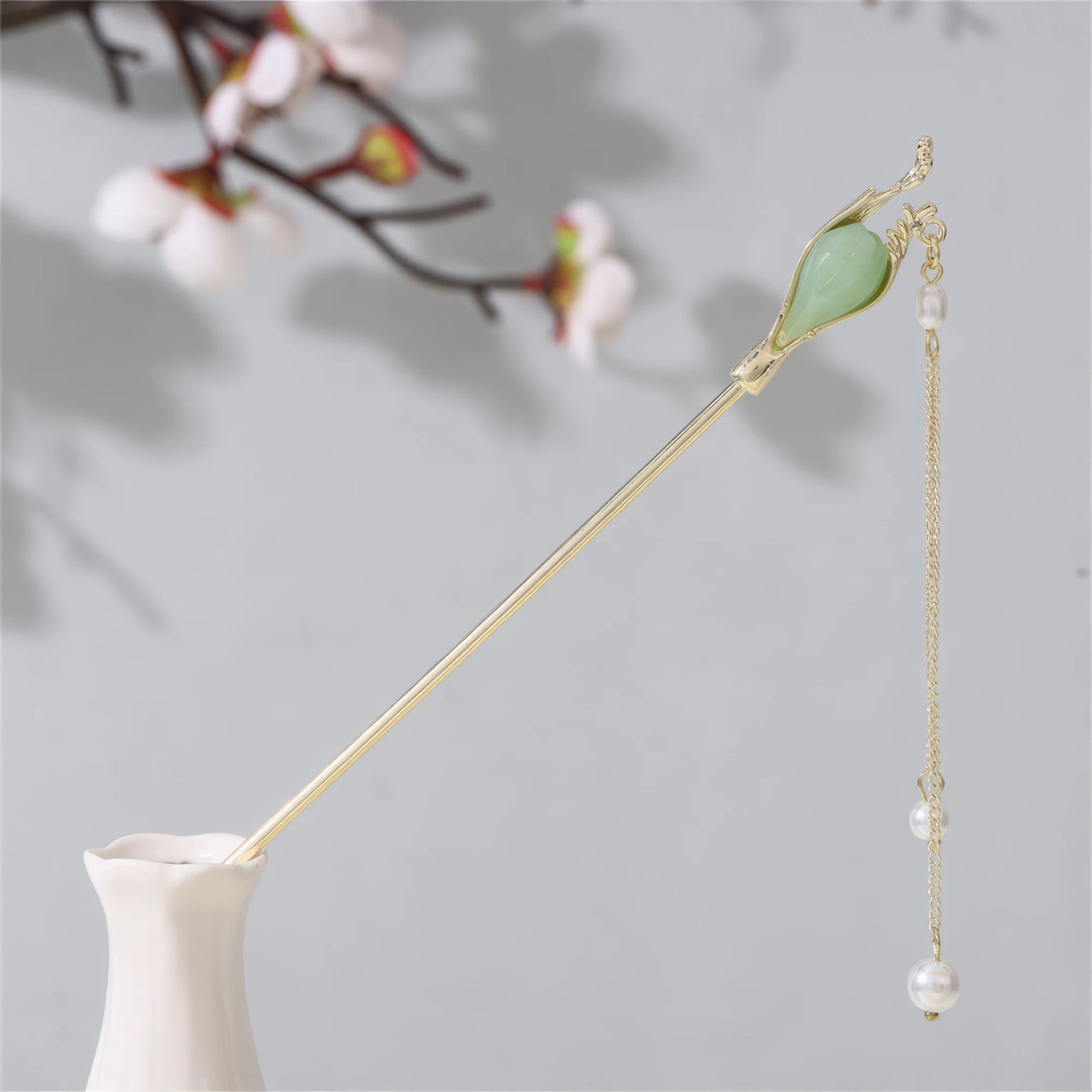 Jianjianjiao hairpin 2, gold rod with pearl and jade, in white vase against light gray background with plum blossoms